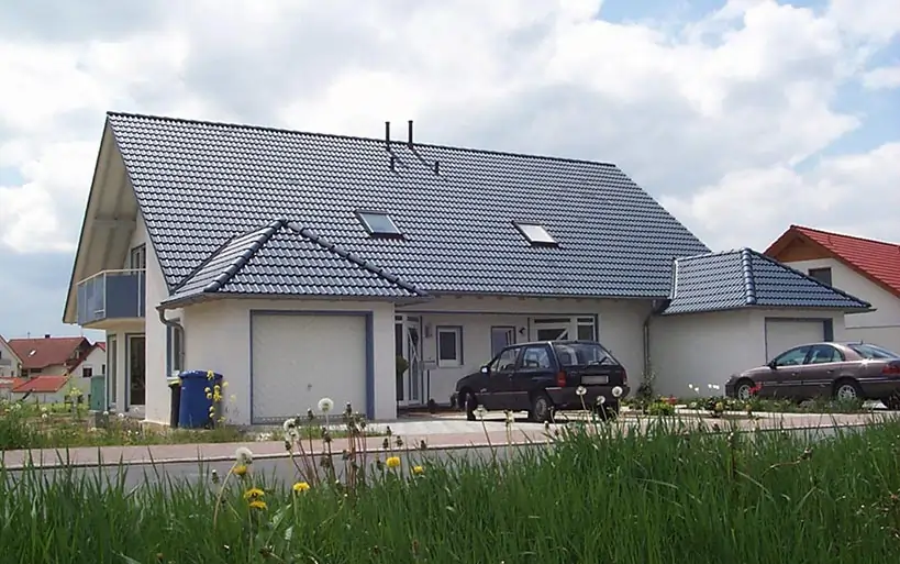 Klassisches Einfamilienhaus mit blauem Satteldach, Doppelgarage und großzügigem Eingangsbereich, errichtet mit dem MAGU Bausatzsystem.