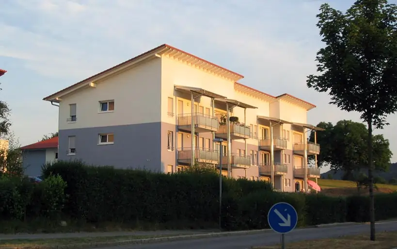 Modernes Mehrfamilienhaus mit mehreren Balkonen und zweifarbiger Fassade in ruhiger Wohngegend.
