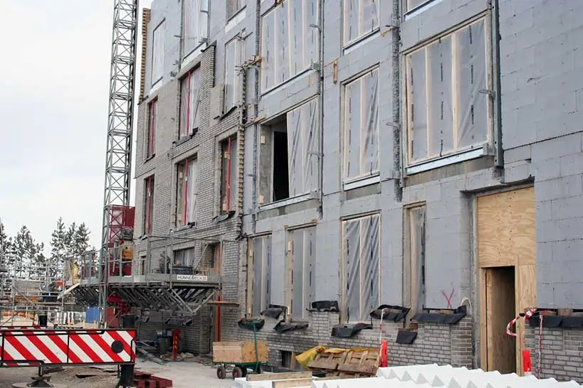 Detailansicht der Außenfassade mit MAGU ReForm Wandsystem und eingerüsteter Baustelle